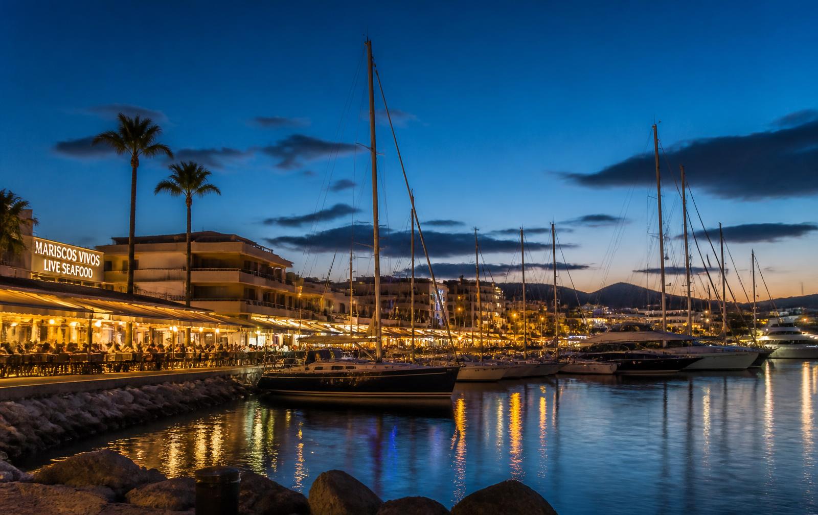 Fuengirola marina at dusk with moored boats and lit restaurant terraces