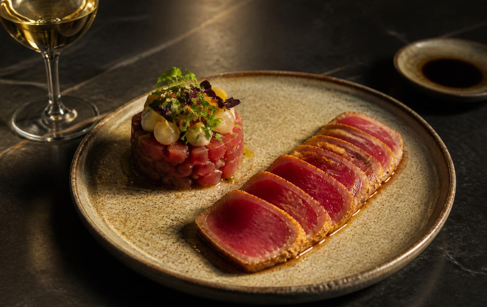 Bluefin tuna tartar and tataki plated with a glass of white wine